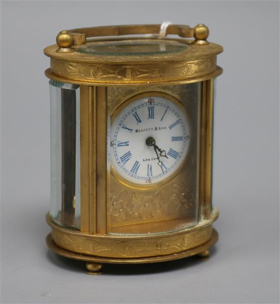 A 20th century oval engraved brass carriage timepiece, the circular dial marked Elliot and Son London height 8cm